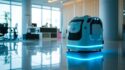 A futuristic autonomous robot with blue accent lighting is positioned in a modern office lobby with reflective flooring; office furniture and large windows are visible in the background.
