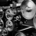 Black and white image of an assortment of interlocking metal gears and machinery parts.