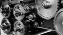 Black and white image of an assortment of interlocking metal gears and machinery parts.