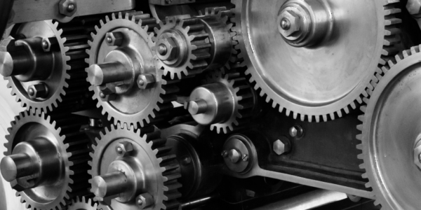 Black and white image of an assortment of interlocking metal gears and machinery parts.